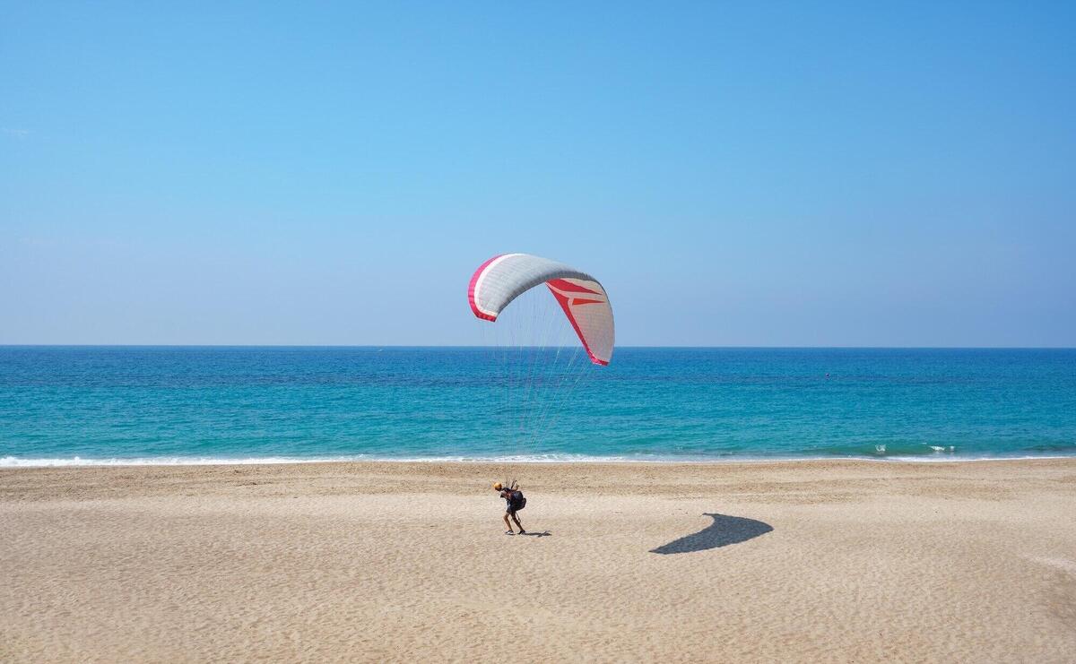 Paraglider flying over the sea shore with blue water and sky on horison. View of paraglider and Blue Lagoon in Turkey.