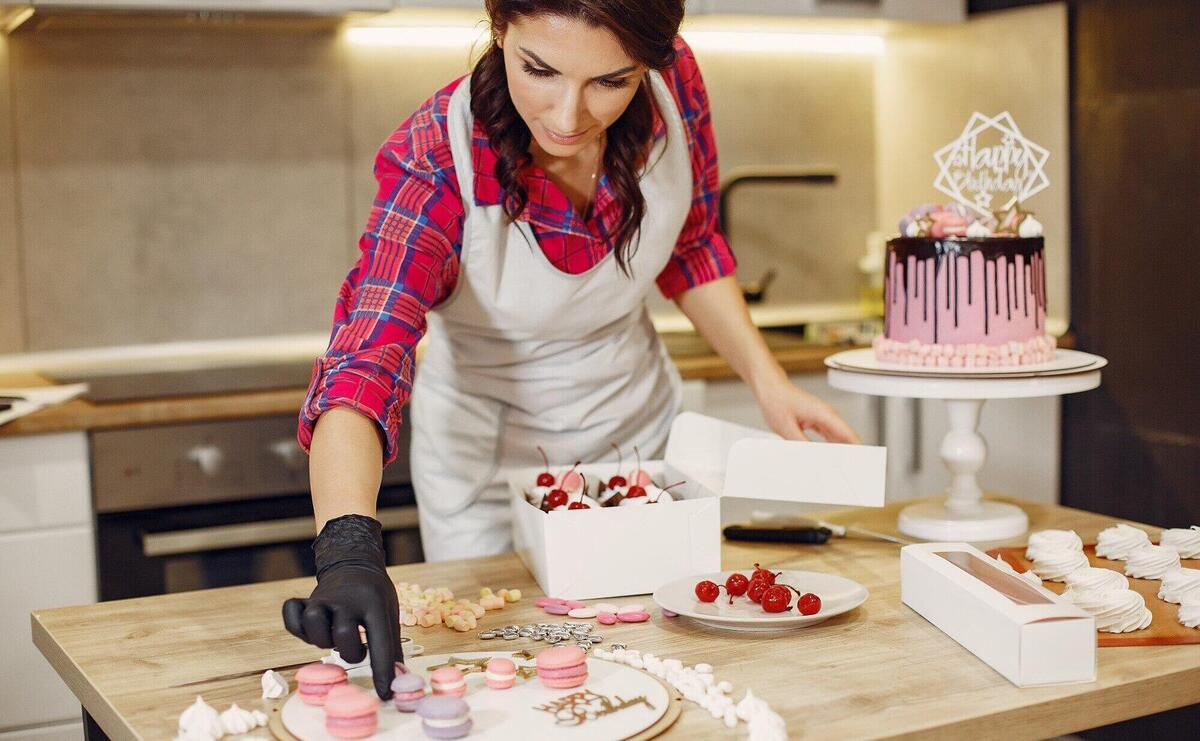 Confectioner in a uniform decorates the cakes