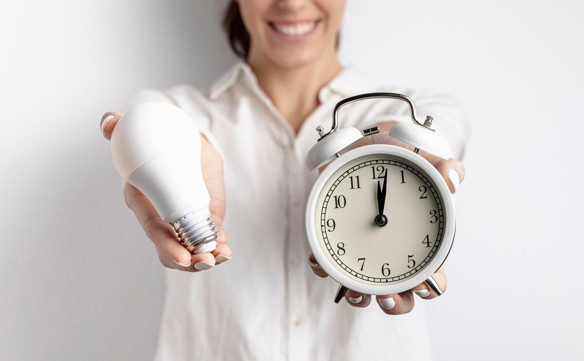 Defocused smiley woman holding light bulb and clock