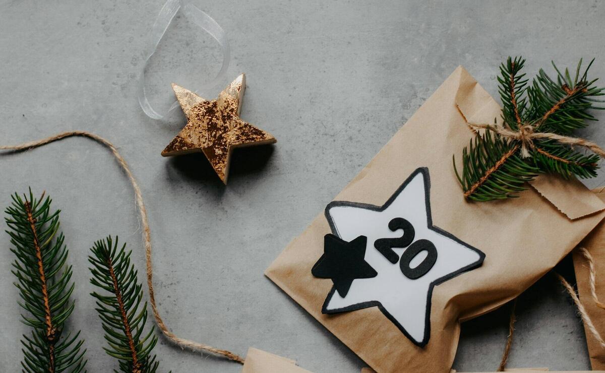 Aesthetic holiday gift packaging with stars on a gray background, featuring evergreen branches.